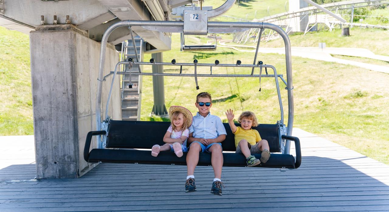 在怀俄明州杰克逊 Snow King Chair Lift 缆椅上笑容满面的三个孩子 在怀俄明州杰克逊 Snow King Chair Lift 缆椅上笑容满面的三个孩子